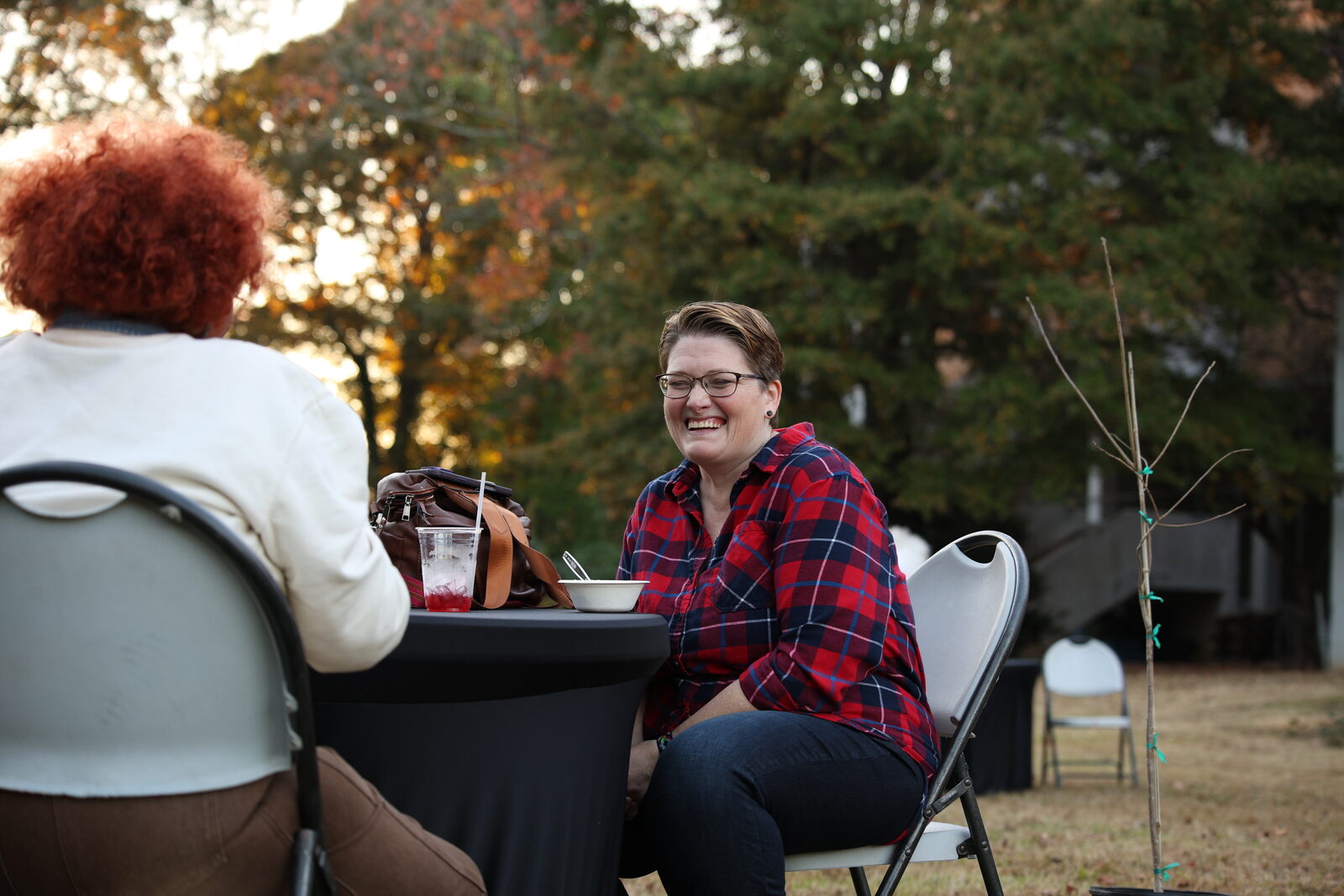 Neighbors talking at a table on the farm in the evening light
