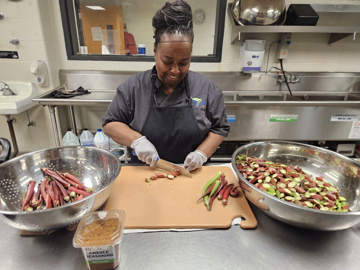 Chef Monica Stinson cutting red and green okra at a steel kitchen counter