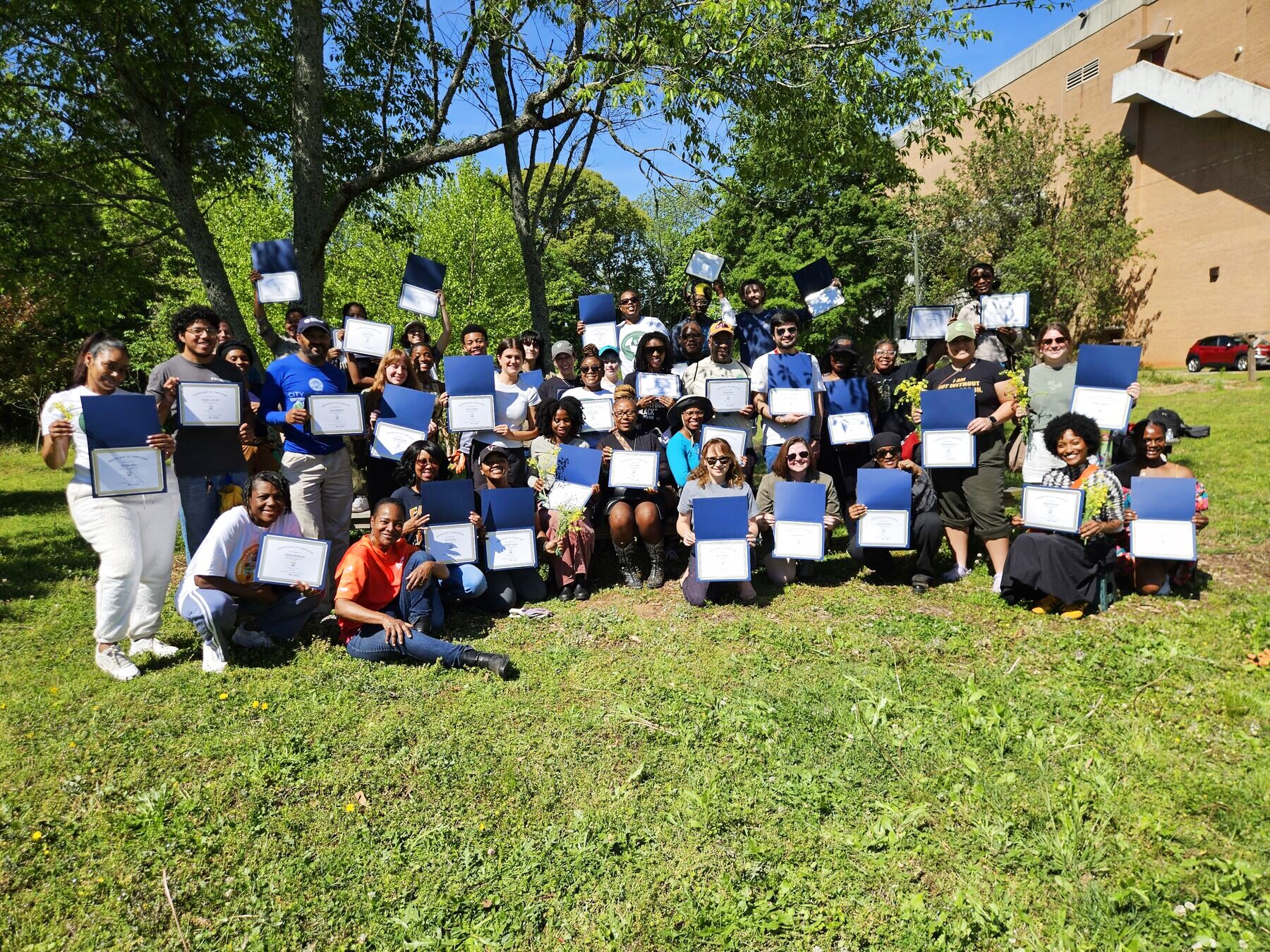The Sustainability Ambassadors cohort holding certificates on the farm lawn