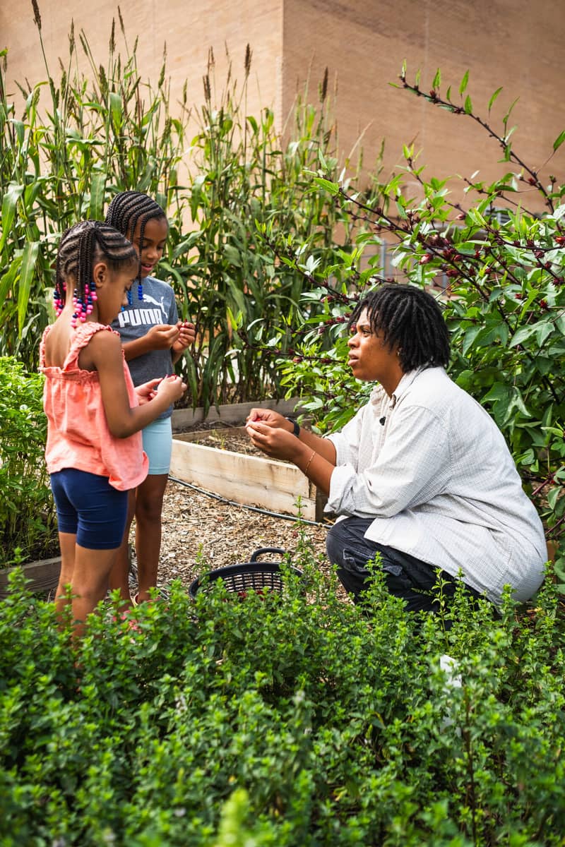 An educator kneeling with two students in the rows