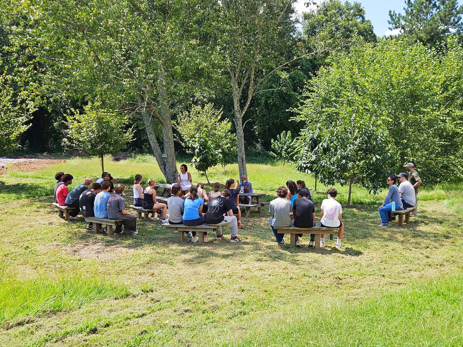 People sitting together under the trees at the farm
