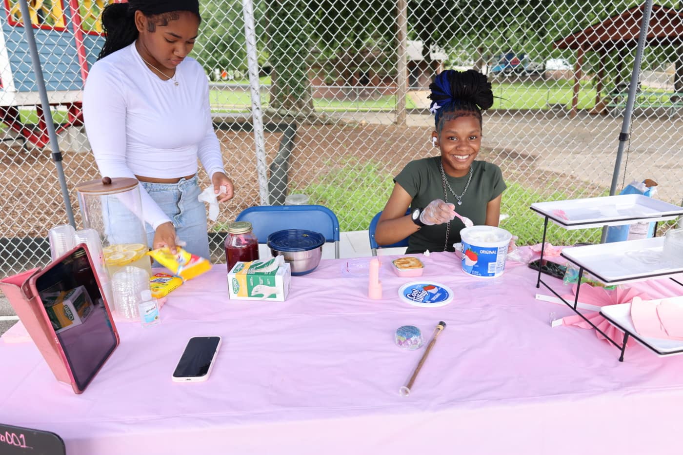 Two students serving a customer from behind their booth at the market
